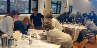 Three stables are lined up after one another, all surrounded by adults working together on paper during a stakeholder event.